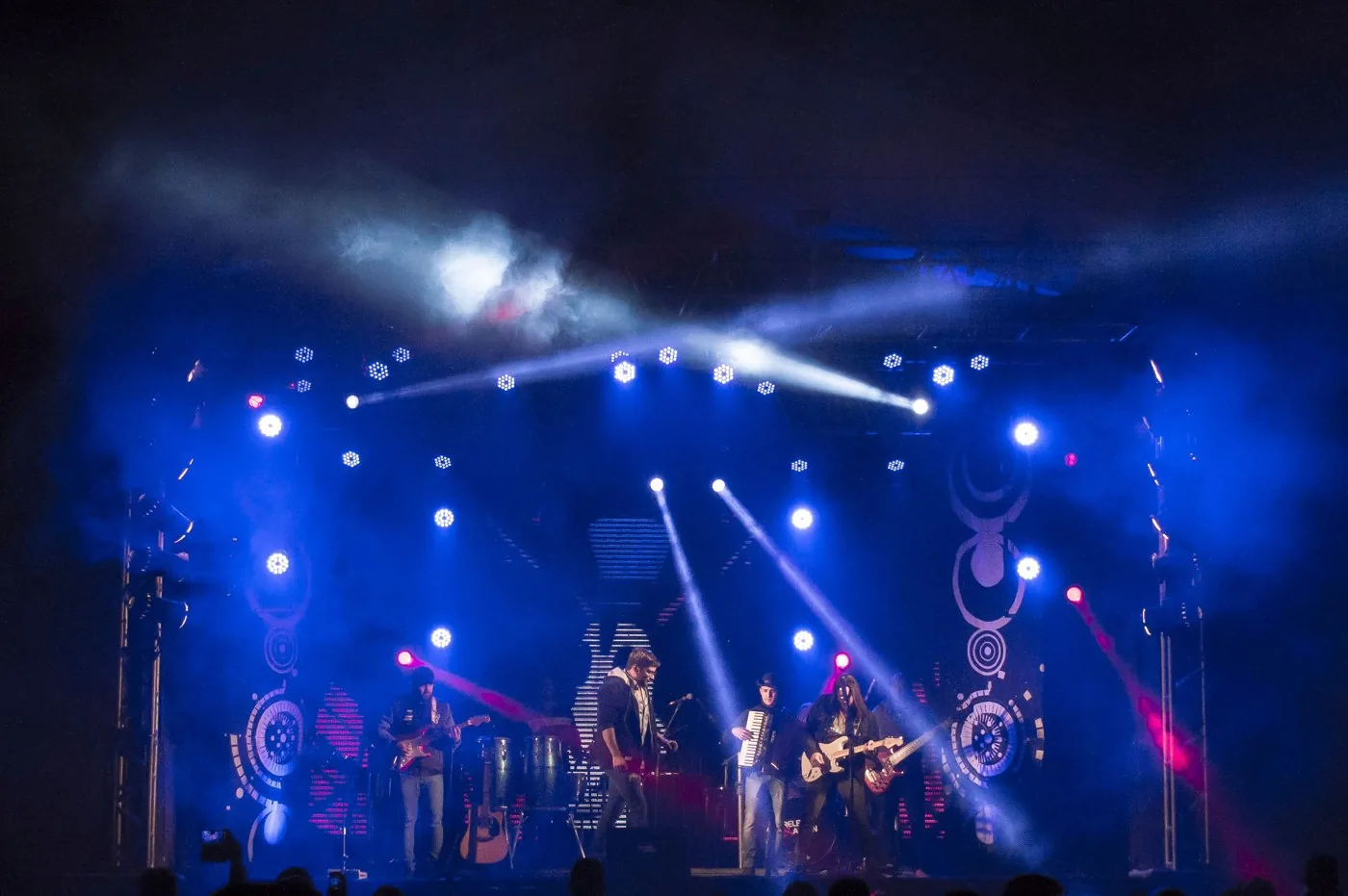 Banda y sección rítmica para playback Banda en un escenario de festival con iluminación azul y público.